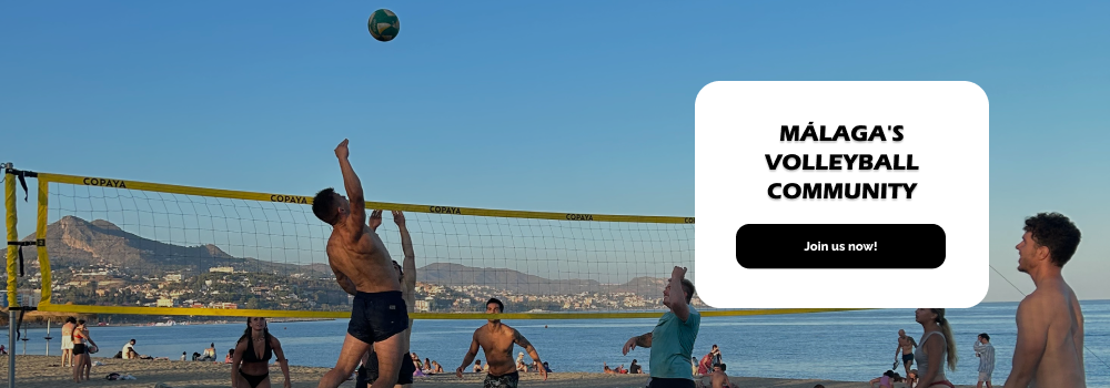 People playing beach volleyball in Málaga city in Huelin. A man jumps to hit the volleyball on the opposite side of the court.