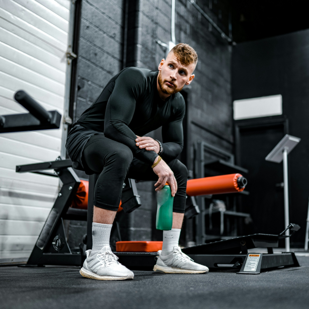 a personal trainer sitting on a bench looking away, hosting sports activities on Flakex.